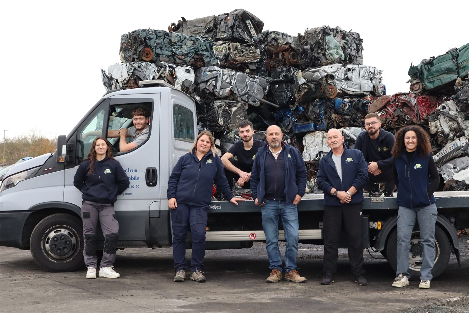 L'équipe complète de MPO Recycling devant un camion chargé de véhicules compactés sur le site de Peltre