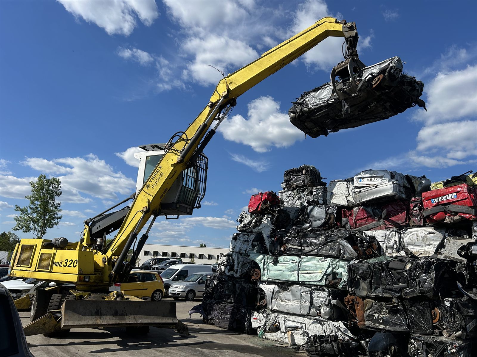 Grue de manutention MPO Recycling traitant des véhicules hors d'usage compactés dans la zone de broyage du centre VHU agréé de Peltre